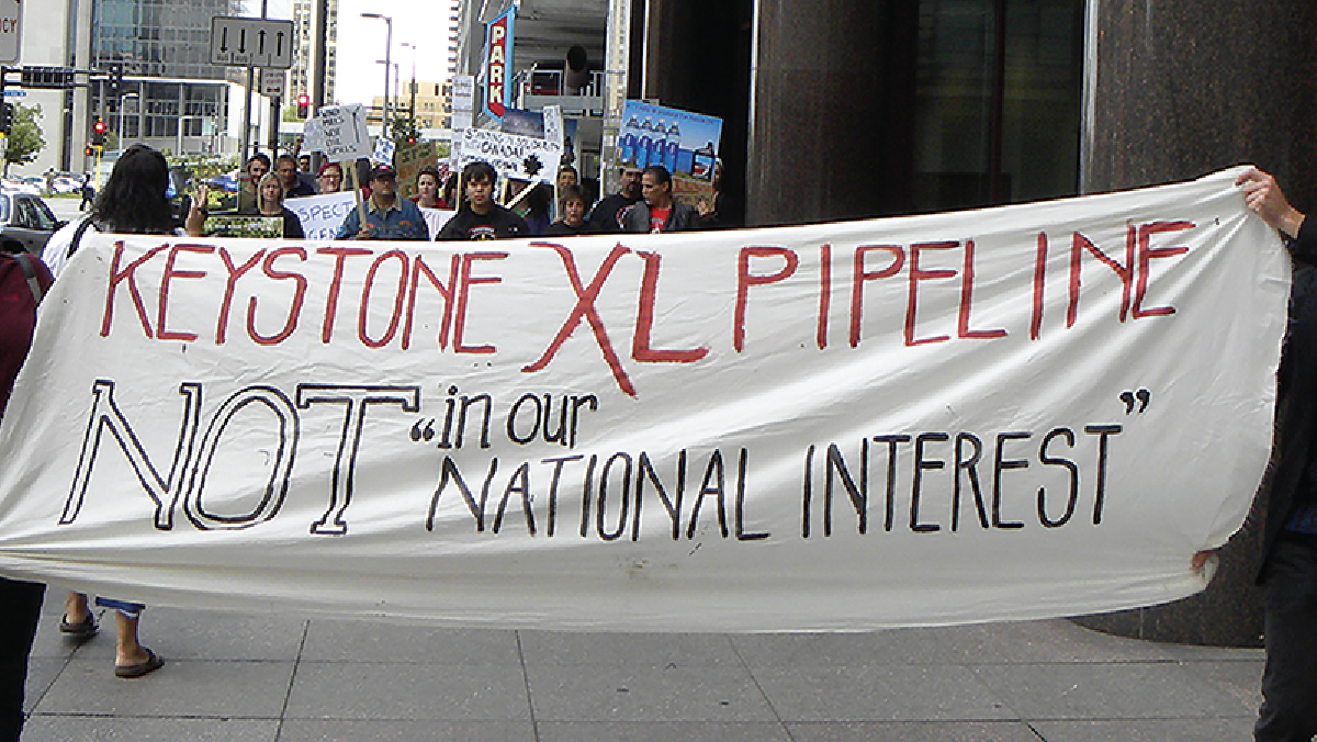 Fólk heldur á borða með áletruninni „Keystone XL pipeline not in our ‘national interest’“ (Keystone XL-olíuleiðslan þjónar ekki „þjóðarhagsmunum“ okkar).