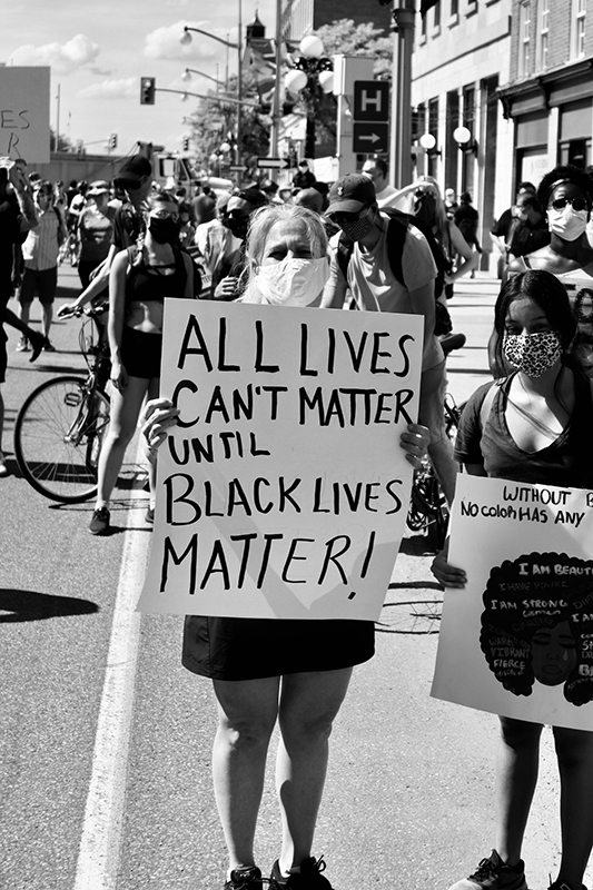 Kona heldur á skilti til stuðnings Black Lives Matter-hreyfingunni