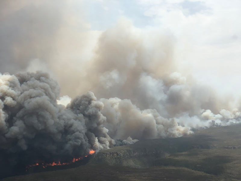 Landslag séð úr fjarlægð með gríðarlegum reykskýjum sem stíga upp af eldum á jörðu niðri.
