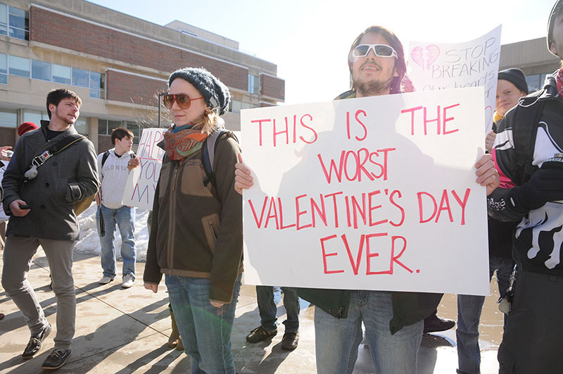 Hópur mótmælenda stendur saman. Einn heldur á skilti með ensku áletruninni „This is the worst Valentine's Day Ever“ („Þetta er versti Valentínusardagur allra tíma“).