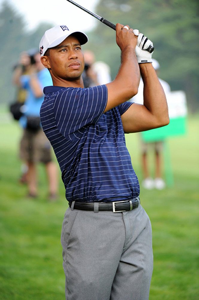 Ljósmynd af kylfingnum Tiger Woods sem heldur golfkylfu á lofti á golfvelli eftir að hafa slegið kúlu
