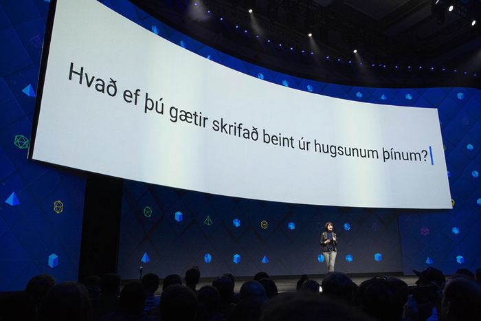 Regina Dugan, varaforseti verkfræðimála hjá Facebook, stendur á sviði undir stórum skjá. Á skjánum stendur: „Hvað ef þú gætir skrifað beint úr heilanum?“