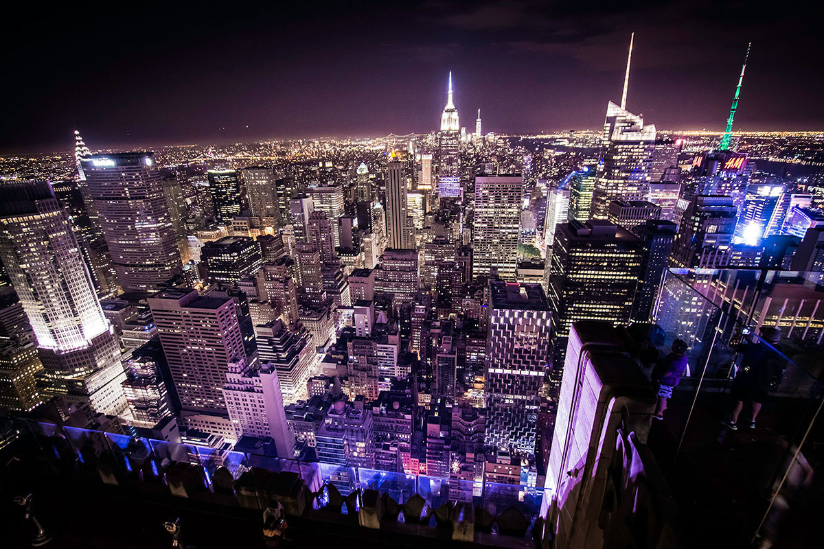 Næturmynd sýnir sjóndeildarhring New York með upplýstum skýjakljúfum.
