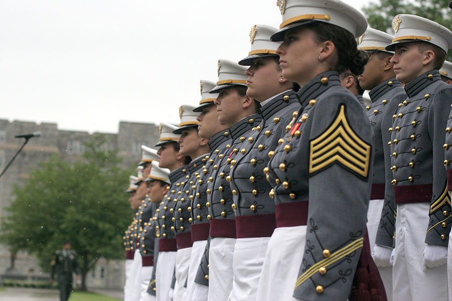 Hópur liðsforingjanema við West Point í gráum hátíðarbúningum og með hvítar derhúfur. Hvert þeirra ber rauðan borða um mittið til merkis um að það sé á lokaári.