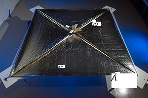 NanoSail er sýnt með útbreiddu ferhyrndu segli og litlum gervihnetti í miðjunni.