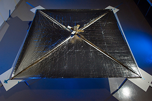 NanoSail er sýnt með útbreiddu ferhyrndu segli og litlum gervihnetti í miðjunni.