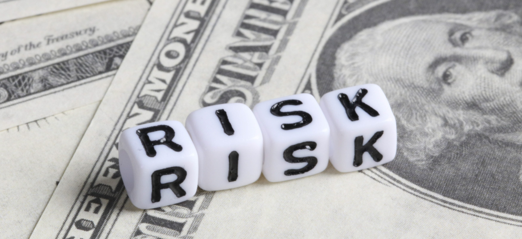 Bókstafateningar mynda enska orðið „RISK“ ofan á bandarískum dollaraseðlum.