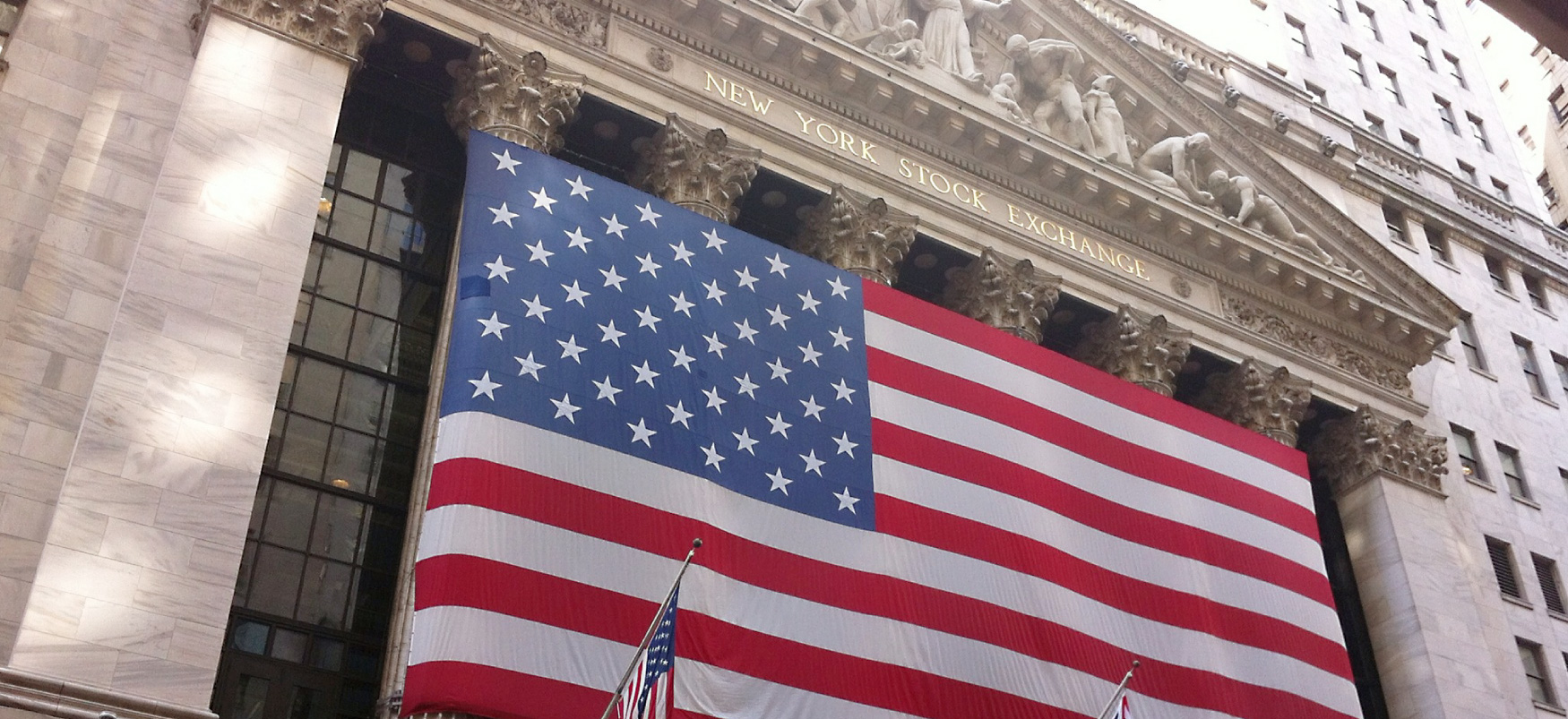 Stór bandarískur fáni hangir yfir inngangi kauphallarinnar í New York.