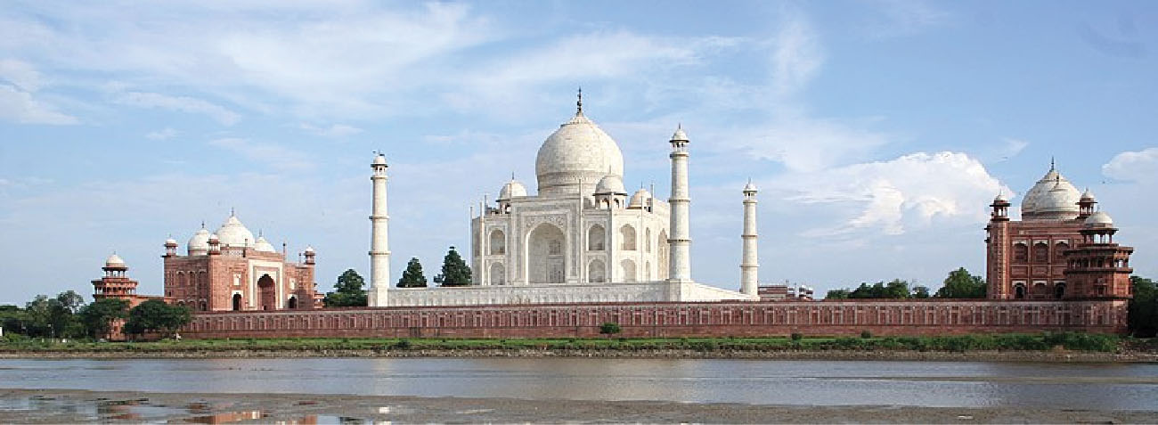 Taj Mahal er fyrir miðri ljósmyndinni. Beggja vegna Taj Mahal stendur moska. Yamuna-fljótið sést í forgrunni.
